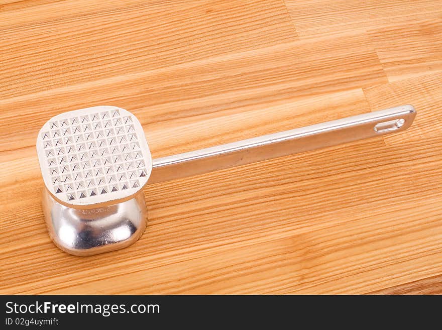 Aluminium meat tenderizer on wooden background.