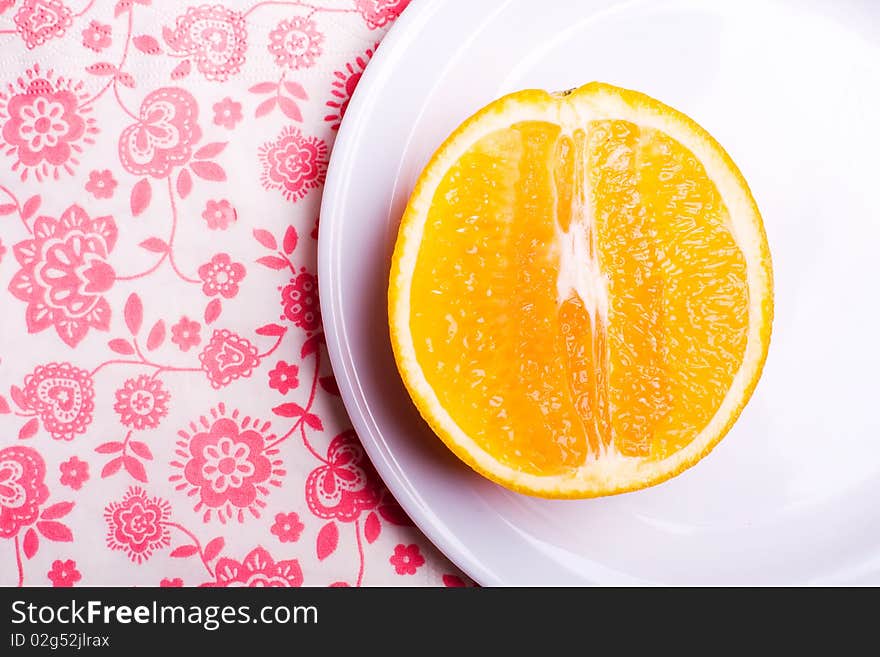 Orange on plate on napkin with flowers