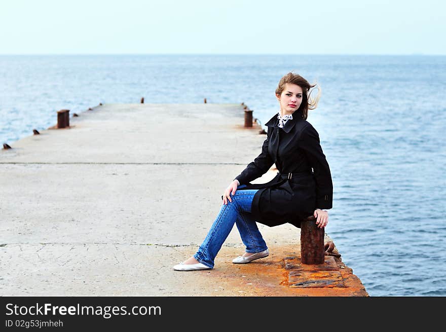 Teen girl sitting on the dock in windy weather