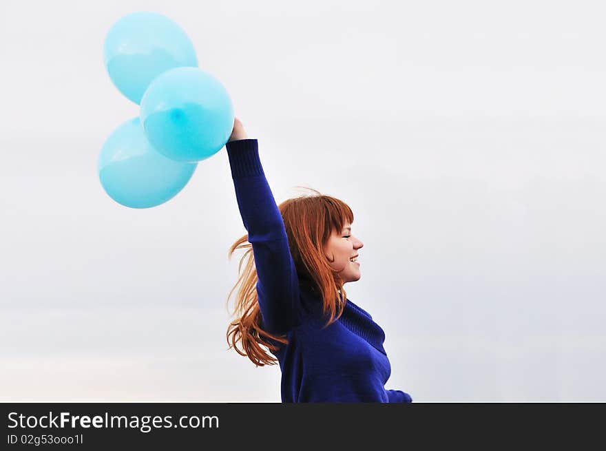 Redheaded girl running with balloons over the sky