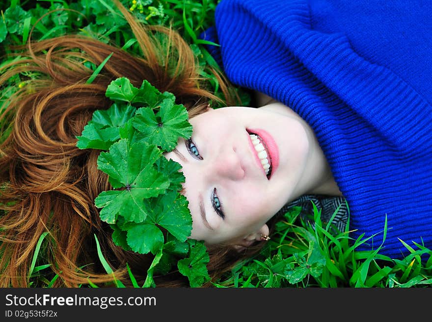 Redheaded girl laying on the green grass with crown from leaves. Redheaded girl laying on the green grass with crown from leaves