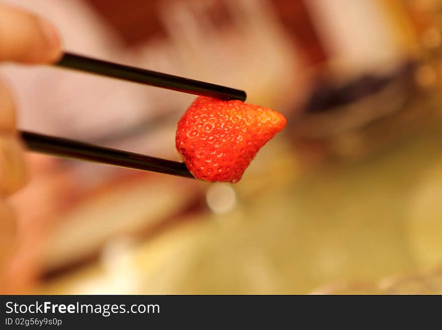 A man holding strawberry by chopsticks at chinese restaurant, Beijing. A man holding strawberry by chopsticks at chinese restaurant, Beijing