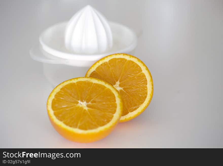 Orange fruit sliced in half with white plastic juicer at the background. Orange fruit sliced in half with white plastic juicer at the background.