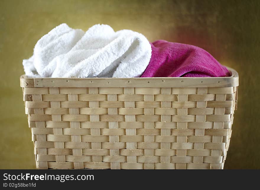 Wooden basket with white and pink towels in front of golden wall. Wooden basket with white and pink towels in front of golden wall.