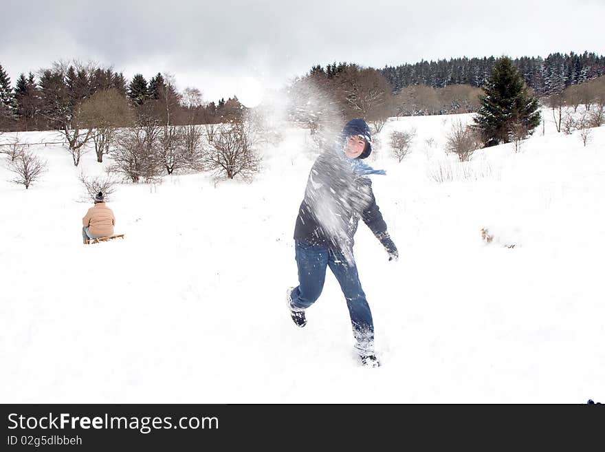 Child is fighting with snowballs in winter