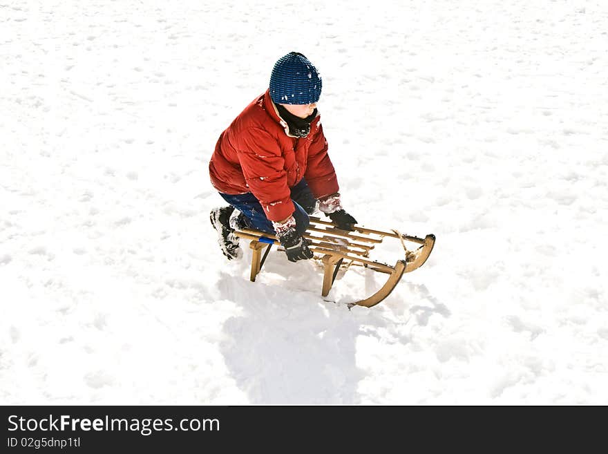 Young boy in red jacket is sledding down the hill in winter. Young boy in red jacket is sledding down the hill in winter