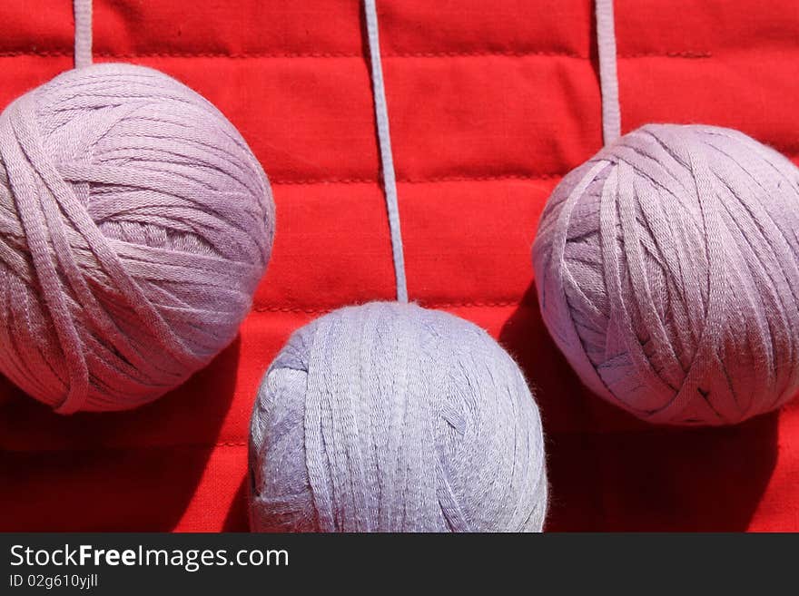 Threads, threads in the coil, skeins of thread, three large skein of knitting, knitting with natural threads, skeins of purple yarn, on a red background, leisure, lifestyles, family at home, crochet, meditative exercise