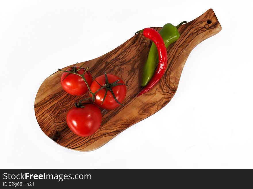 Three fresh red tomato and Chili pepper on breadboard