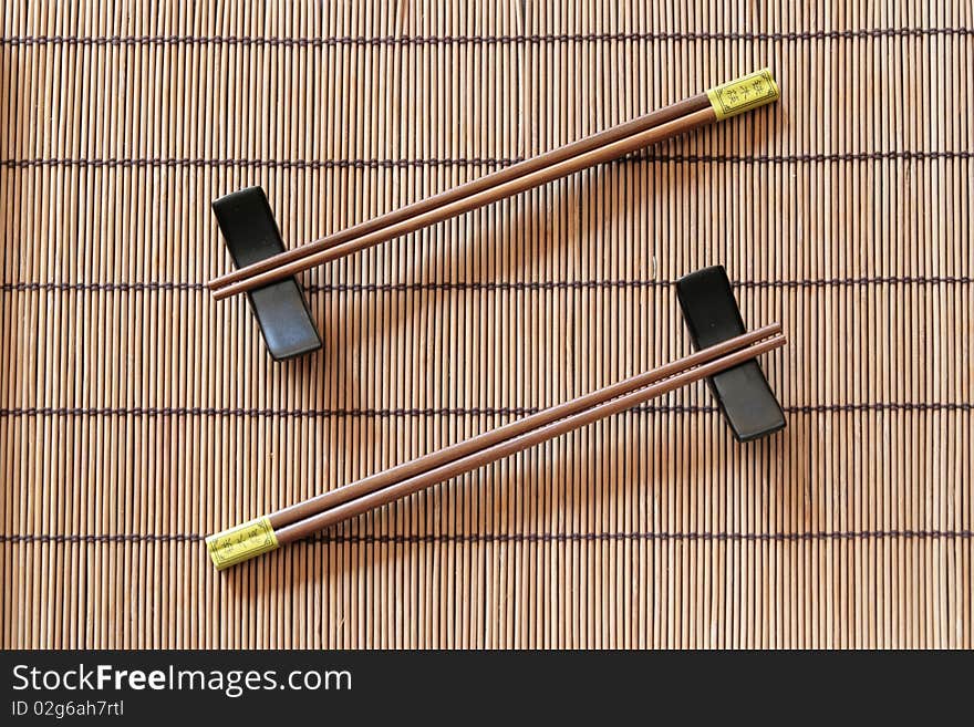 Two couples of chopsticks on a bamboo place mat