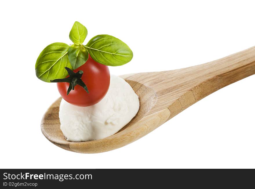 Tomato, mozzarella and basil on a wooden spoon close up. Tomato, mozzarella and basil on a wooden spoon close up