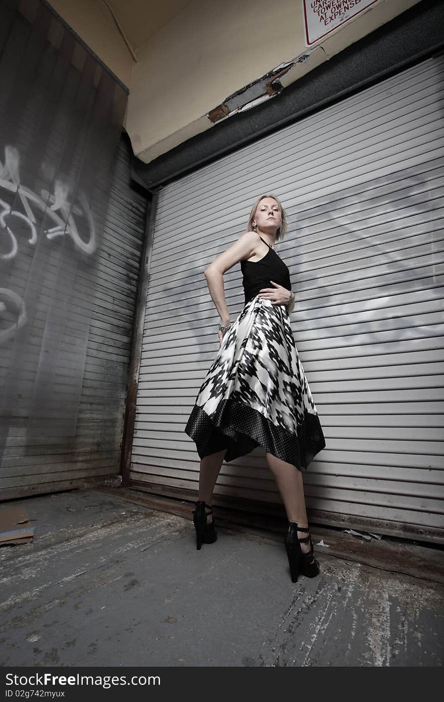 Young woman posing by an old abandoned building with graffiti. Young woman posing by an old abandoned building with graffiti