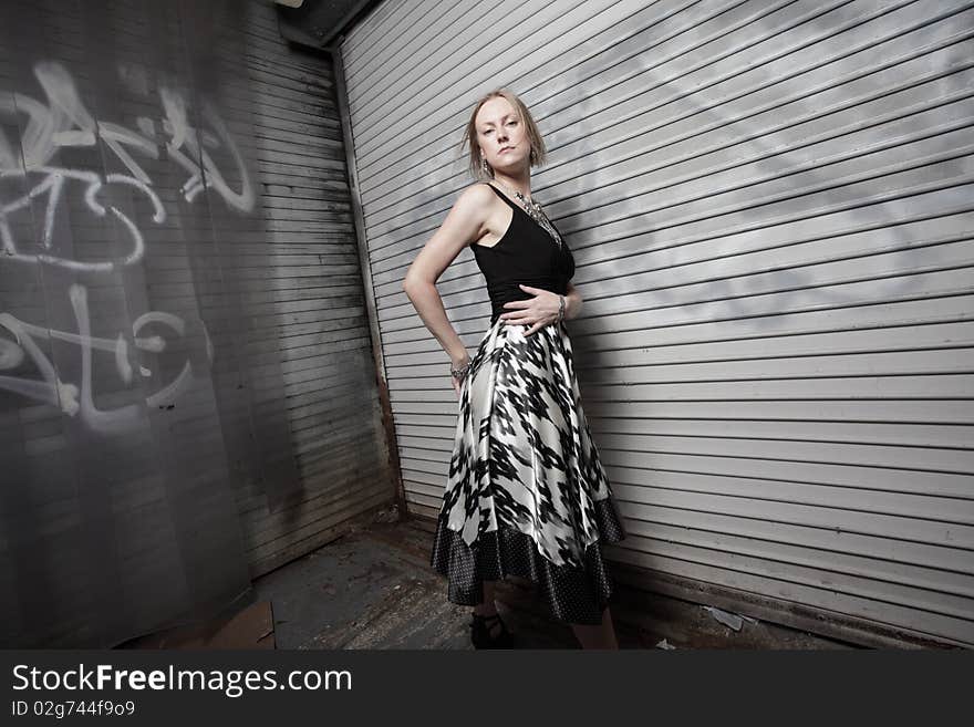 Young woman posing by an old abandoned building with graffiti. Young woman posing by an old abandoned building with graffiti