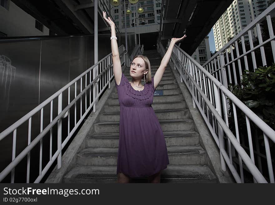 Attractive young woman posing in the city with arms extended outward. Attractive young woman posing in the city with arms extended outward