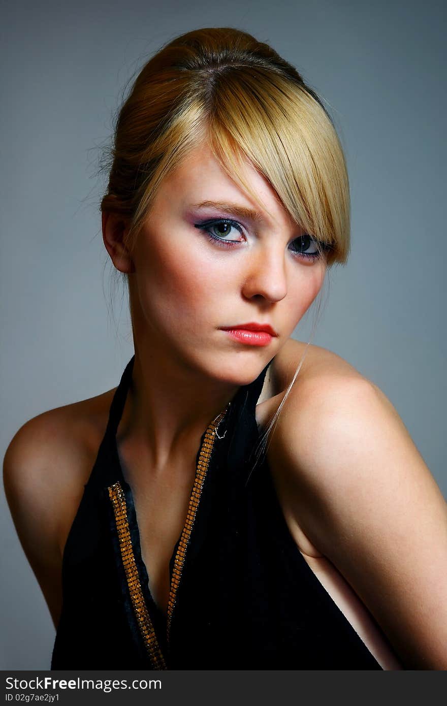 Young woman posing on grey background in black dress. Young woman posing on grey background in black dress