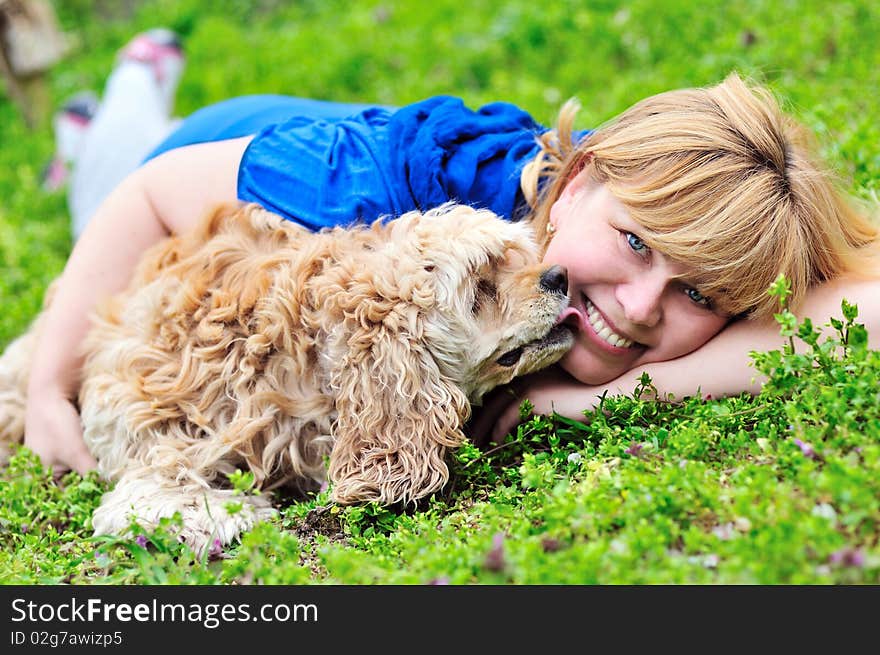 Woman and dog laying on the meadow, dog licking woman's cheek. Woman and dog laying on the meadow, dog licking woman's cheek