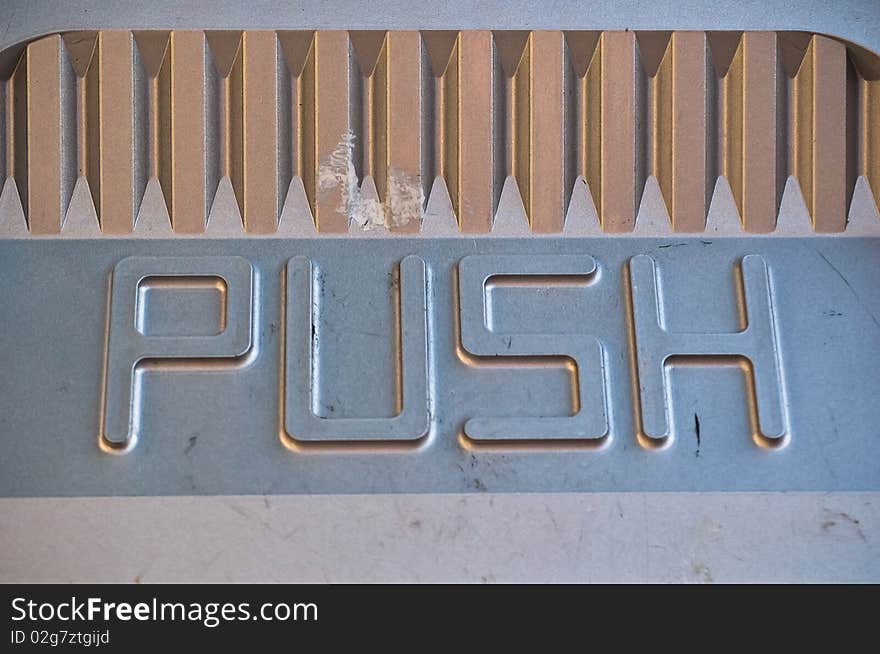 A view of the metal flapping door on a trash can found outodoors. A view of the metal flapping door on a trash can found outodoors.