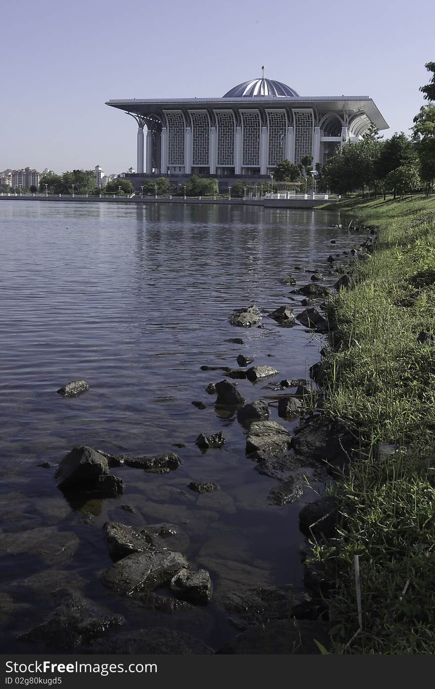 Serene scenery of rocks along lakeside of Putrajaya, Malaysia with Steel Mosque in the background