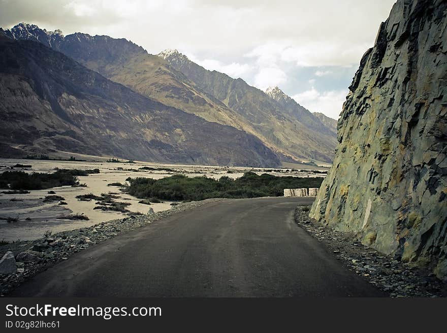 Blind curve on mountain road in Himalaya. Kashmir, India. Mountain range on background.