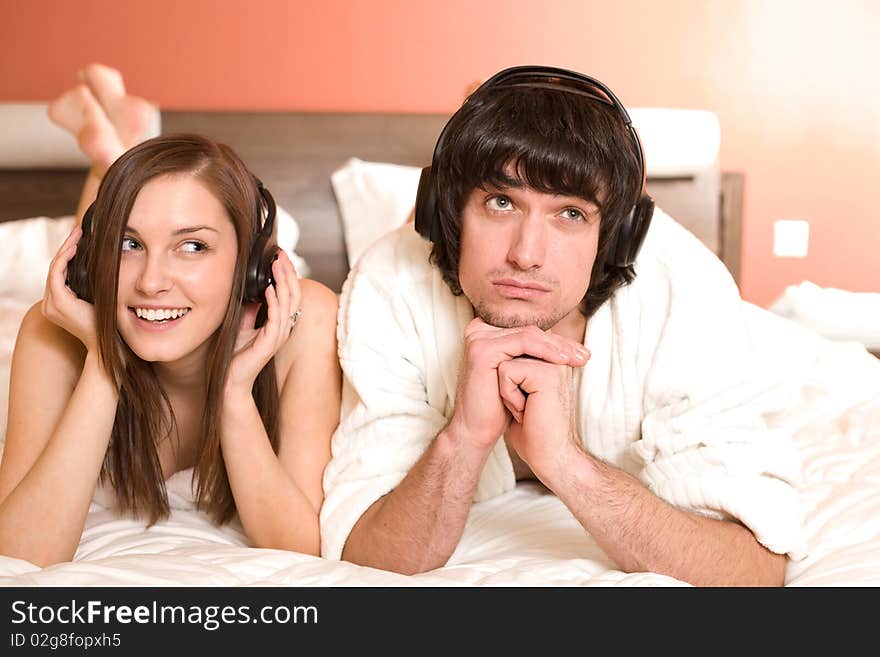 Boy And Girl In Headphones On Bed