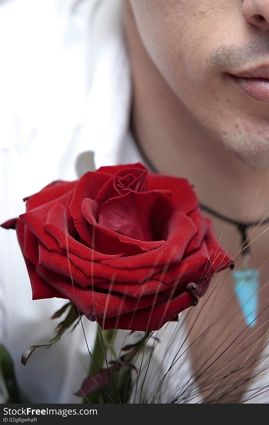 Face of a man in the foreground with a red rose perhaps to donate to their beloved. Face of a man in the foreground with a red rose perhaps to donate to their beloved