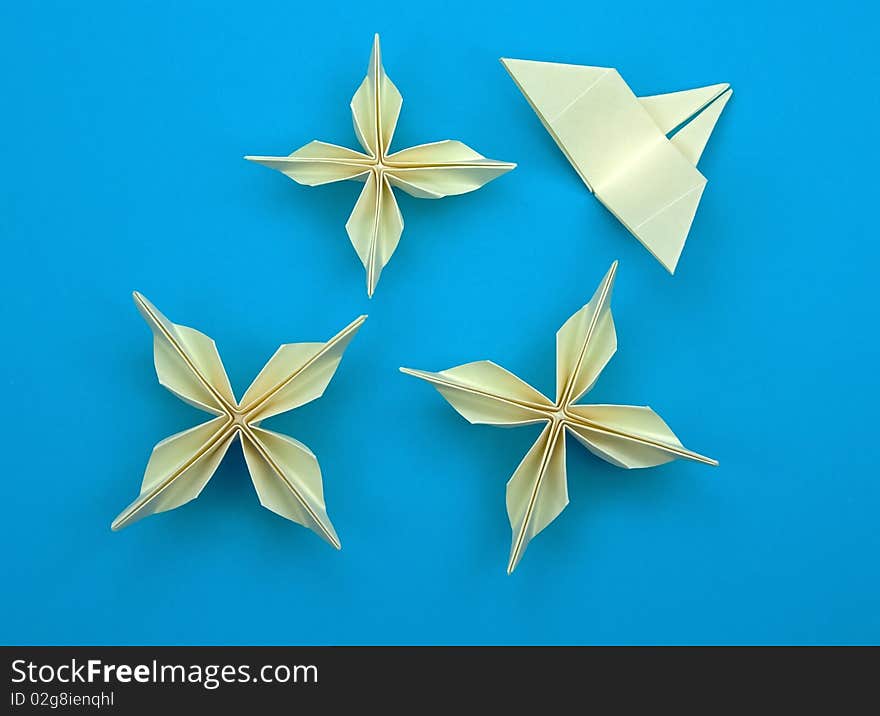 Three origami flowers with a butterfly on a blue background