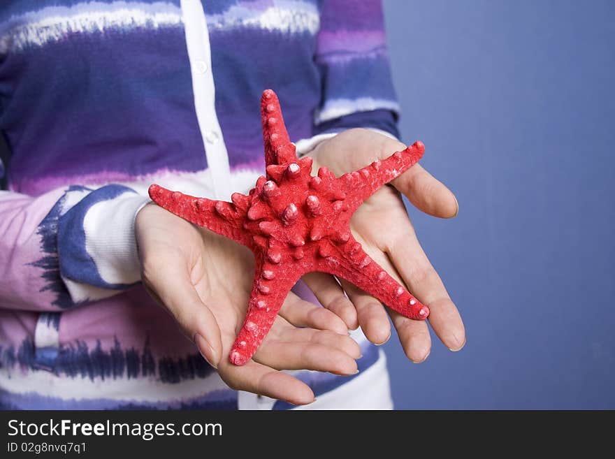 The girl in the room of her hand holding a red starfish. The girl in the room of her hand holding a red starfish