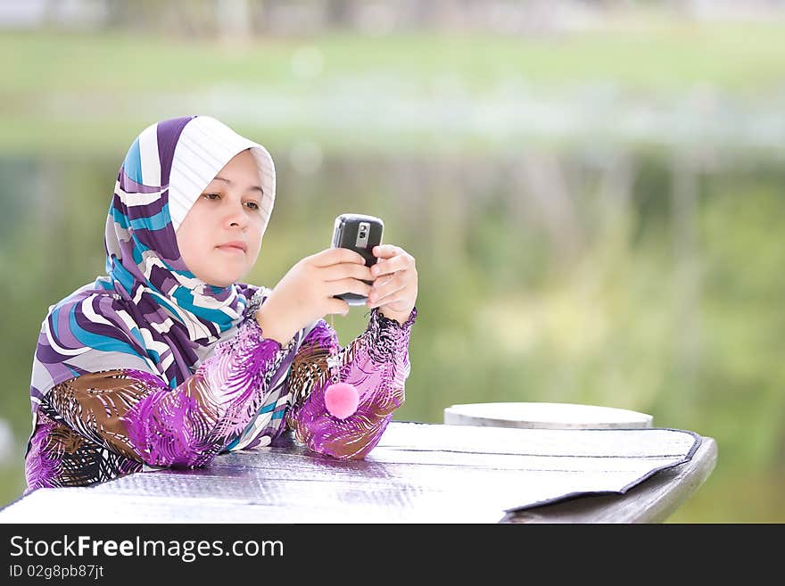 Asean Muslim Women playing her mobile phone. Asean Muslim Women playing her mobile phone