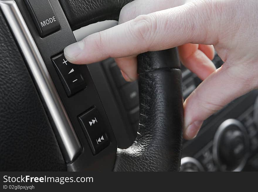 Finger pushing increase volume button on the steering wheel