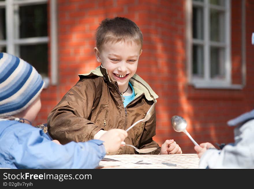 Boys playing with spoons while their`s grandmother preparing lunch. Boys playing with spoons while their`s grandmother preparing lunch