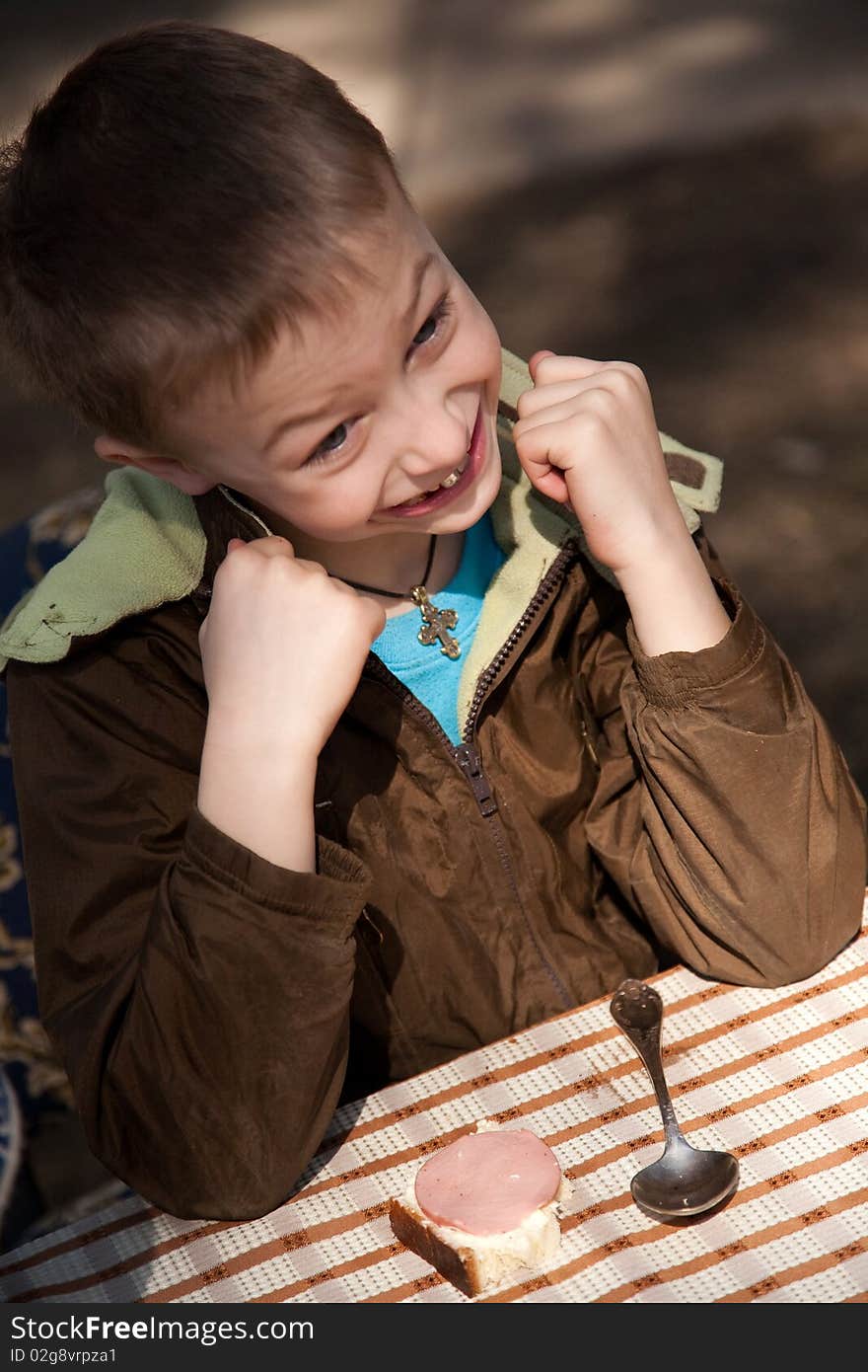 Boy siting at table on the open air and waiting his grandmother with soup. Boy siting at table on the open air and waiting his grandmother with soup