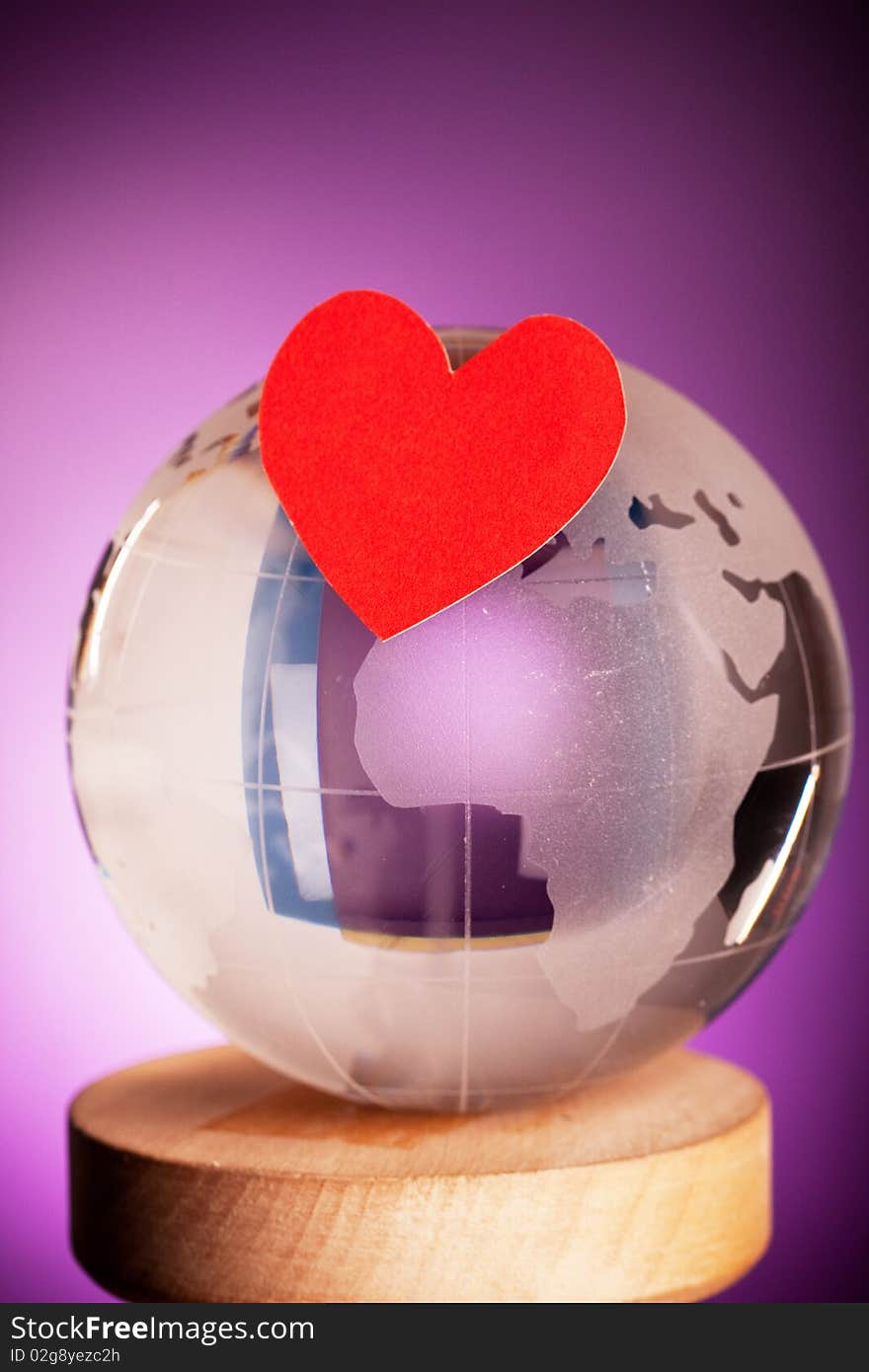 Globe with red heart shot on violet backgorund. Globe with red heart shot on violet backgorund