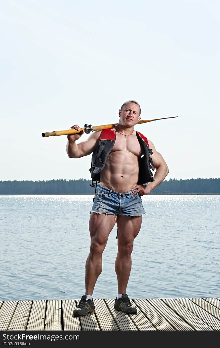 Muscular Man with oar at lake