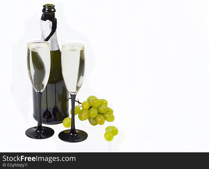 Glasses, bottle of champagne and grapes cluster on white background