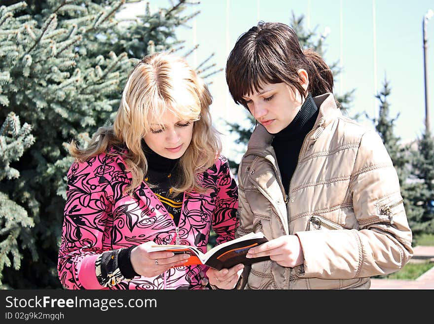 Two girls read the book in a park