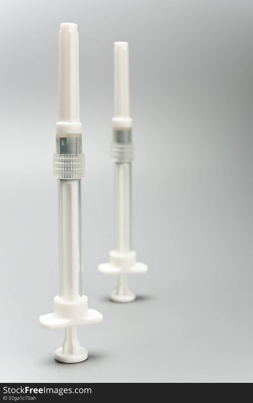 Two syringes on a grey background