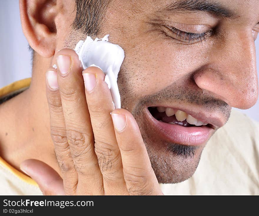 Rubbing shaving cream on face.