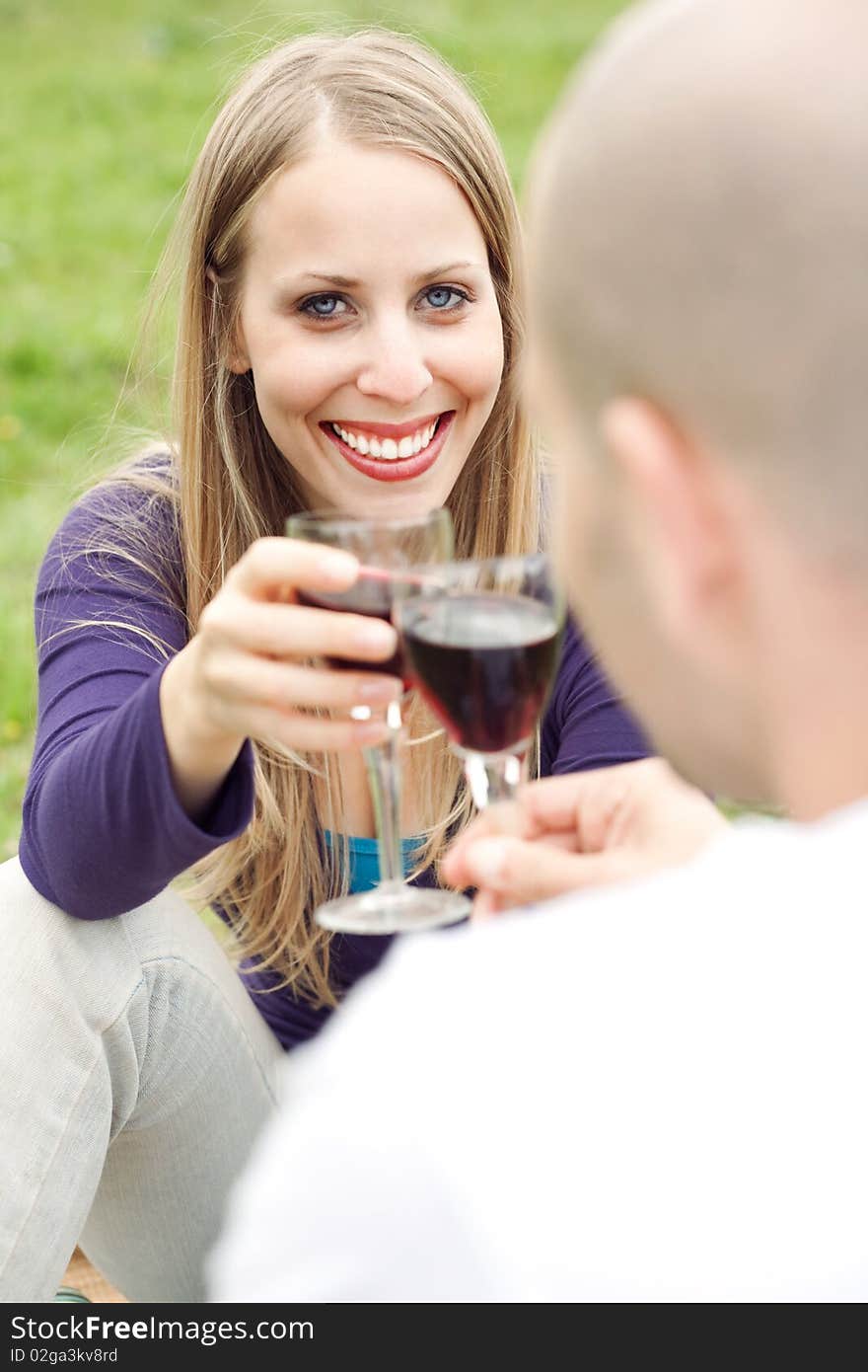 Young romantic couple celebrating with wine in picnic