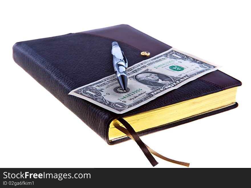 Dark brown leather diary with nacre pen and 2 $ cash on the top of it isolated on white