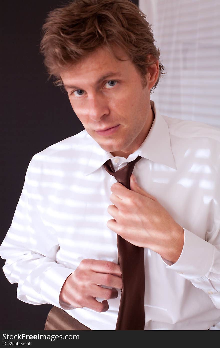 A handsome man fixing his tie and making eye contact with the camera. A handsome man fixing his tie and making eye contact with the camera