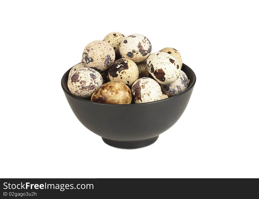 Quail eggs in a bowl of black on a white background