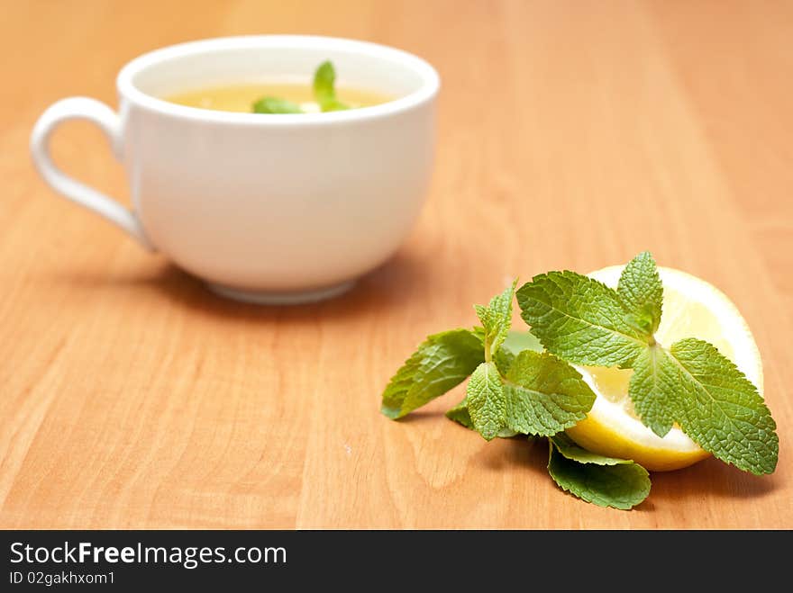 Tea with mint and lemon on a wood background