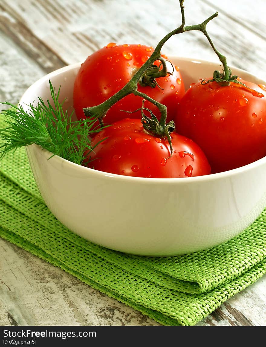 tomatoes with water drops in bowl on wooden