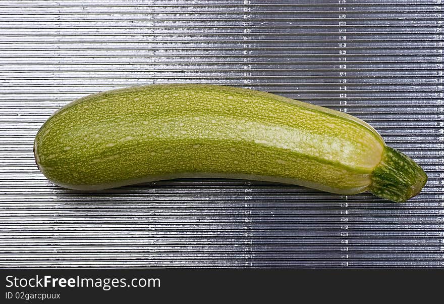 Single green marrow on a ribbed steel background. Single green marrow on a ribbed steel background