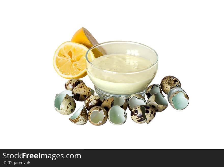 Mayonnaise in a transparent plate around placed shell of quail eggs and cut lemon. Mayonnaise in a transparent plate around placed shell of quail eggs and cut lemon