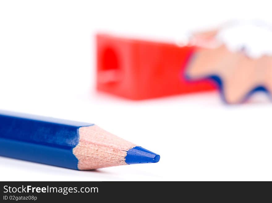 Blue pencil, red sharpener and wood shavings on white background