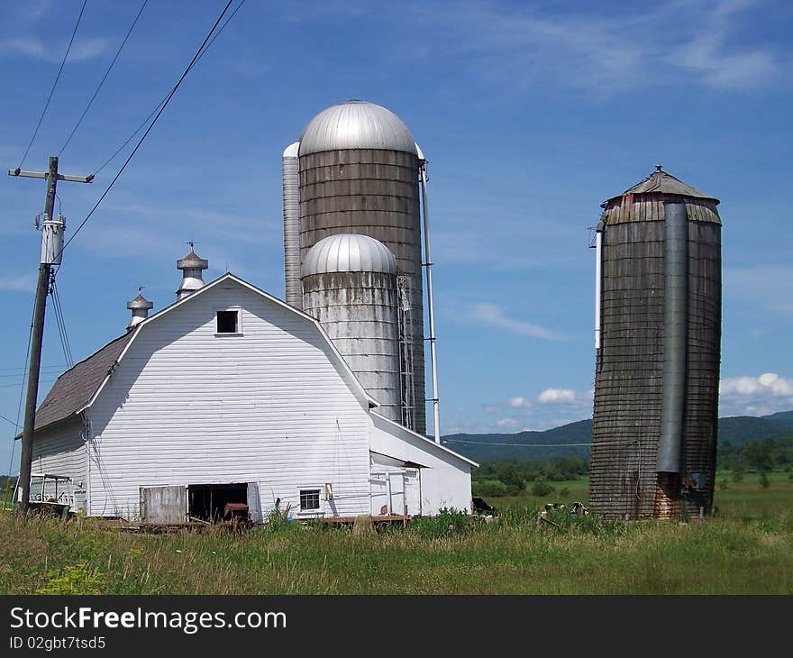 Large barn with three silos in Vermont with the mountains in the background. Large barn with three silos in Vermont with the mountains in the background.