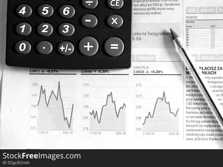 Calculator and pen on the newspaper full of graphs. Calculator and pen on the newspaper full of graphs