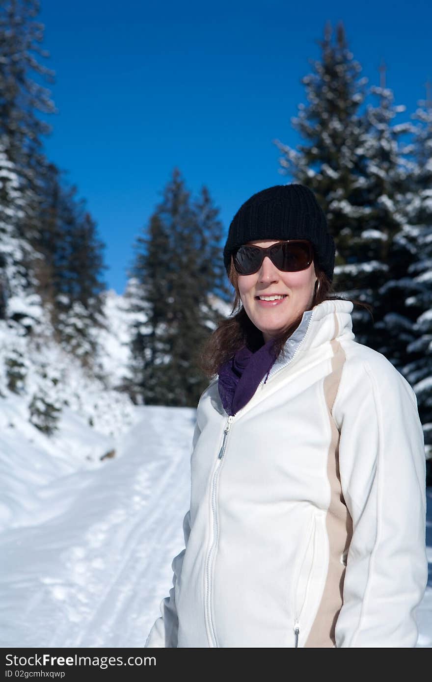 A young woman in a winter wonderland. Lot of snow and trees in the blury background. A young woman in a winter wonderland. Lot of snow and trees in the blury background.