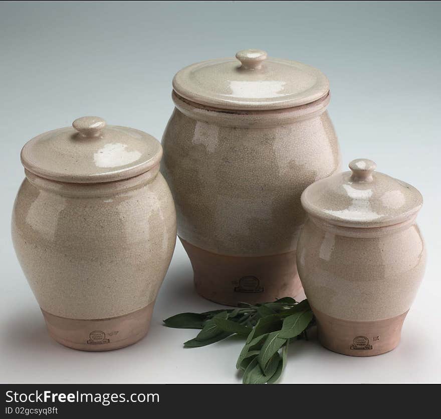 Grouping three clay pots with lids on a gray background