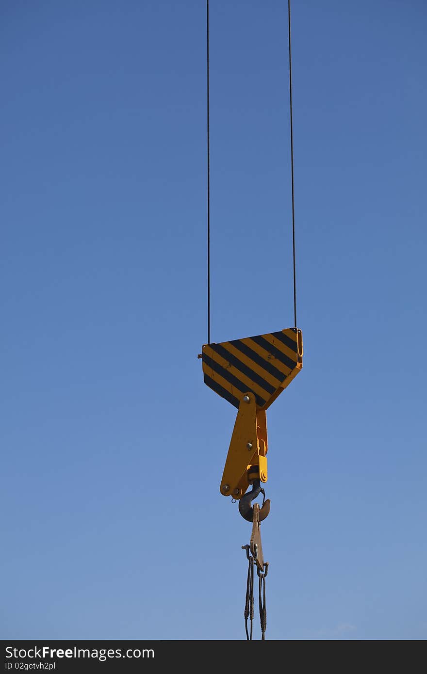 The hook of the crane on blue sky background. The hook of the crane on blue sky background